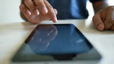 Close-up of a person's hand interacting with a tablet device on a wooden su.. Stock Footage 317736960