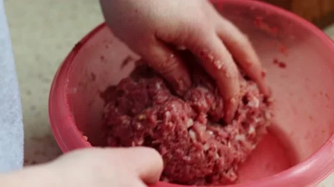 Close-up of a person's hand kneading raw minced meat in a red plastic bowl. Video stock 239014424