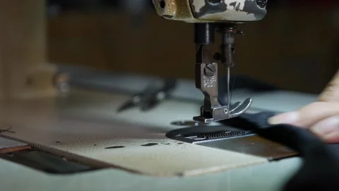 Close-up of a persons hand operating a sewing machine. The focus is on the Stock-Footage 313485883