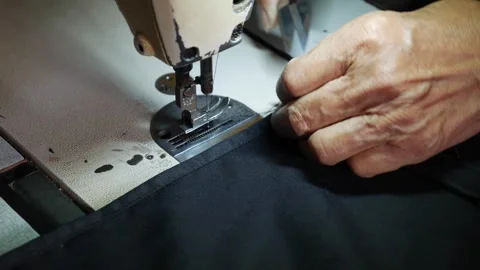 Close-up of a persons hand sewing fabric on a sewing machine. The machine is Video stock 314665048