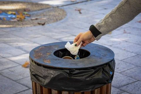 Close up of a person's hand throwing a paper in a trash can Stock Photos