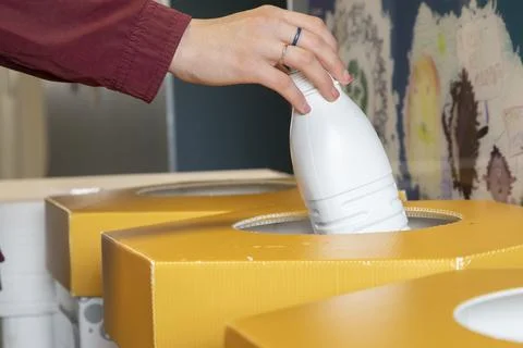 Close-up of a person's hand throwing a used plastic bottle into a special c.. Photos