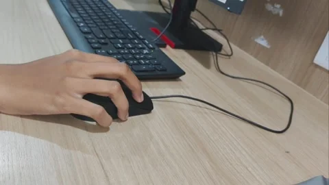 Close-up of a person's hand using a black computer mouse on a wooden desk Stock Footage 335815895