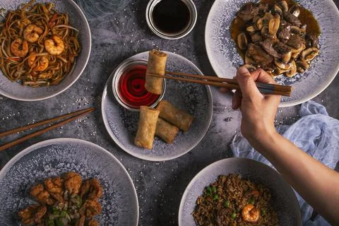 Close up of a person's hand using chopsticks with Chinese food Stock Photos