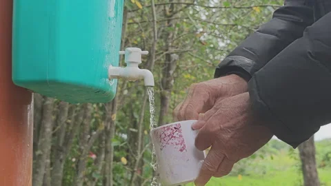 Close up of a person's hands filling a ceramic mug with clean water Stock Footage 343963367