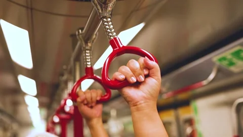 Close up of person's hands gripping red handrails inside moving subway train. Vídeos de archivo 333039034
