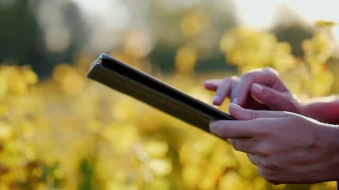 Close up on a person's hands holding and using a tablet computer outdoors i.. Stockbeeldmateriaal 334981316