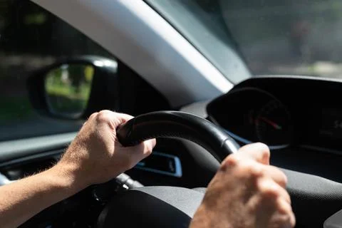 Close-up of a person's hands holding a steering wheel while driving a car Stock Photos