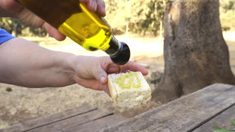 Close up of a person's hands pouring golden extra virgin olive oil from a bottle Stock Footage 343321737