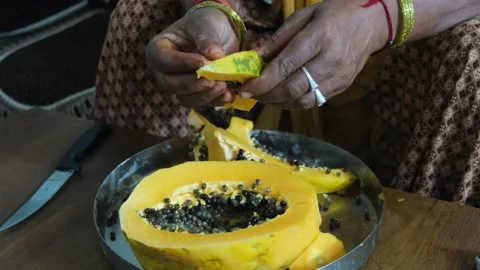 Close-up of a person's hands removing seeds and slicing a fresh ripe papaya Видео 329922000