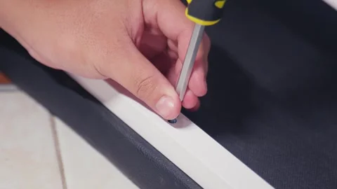 Close-up of a person's hands tightening a screw with a screwdriver during Stockbeeldmateriaal 333316946