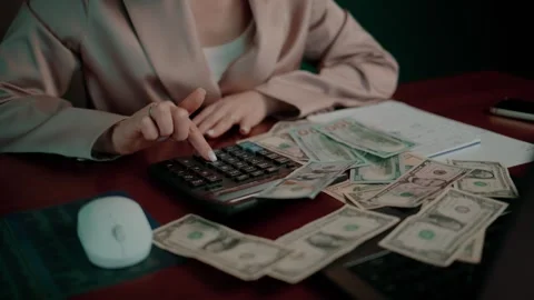 Close-up of a person's hands using a calculator among dollar bills Stock Footage 348122008