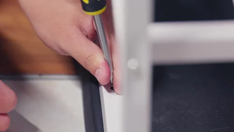 Close-up of a person's hands using a screwdriver to assemble or fix white Stock Footage 333317174