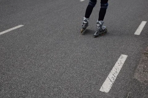 Close-up of person's legs wearing inline roller skates and knee pads skating Stock Photos