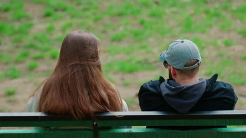 A close perspective from behind shows a couple sitting side by side on a park Vidéo 336816456