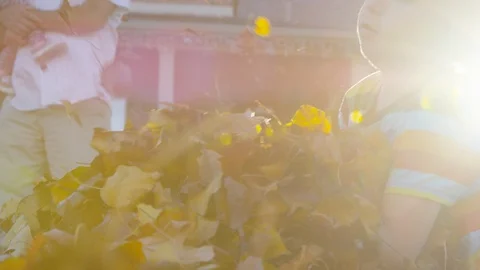 Close perspective of boy throwing arm full of leaves in the air with lens flare Видео 93891168
