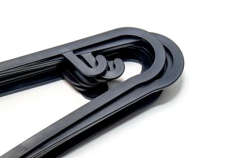 Close-up perspective of a bundle of black plastic clothes hangers set again.. Stockfoto's