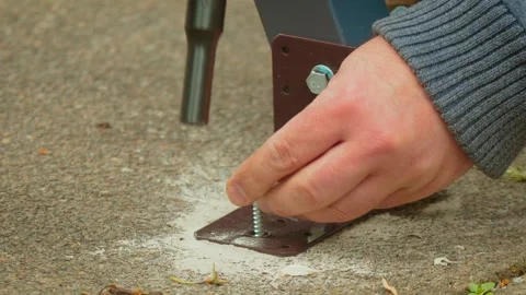 Close perspective of ratchet driving screw into concrete anchor fixing metal Video stock 337418349