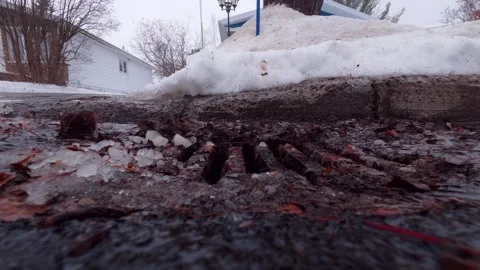 Close Perspective of Snow Thaw and Water Entering Drain Grate Stock Footage 324548498