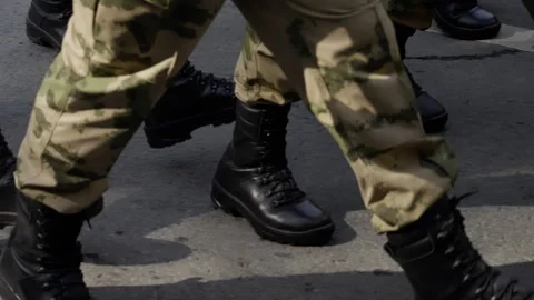 Close-up perspective of uniformed soldiers marching in sync on an outdoor urban Video stock 312674434