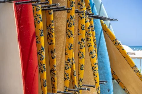 Close up perspective view of diverse surfing boards locked on public stands.. Stock Photos