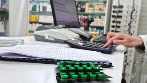 Close-up pharmacy counter and a stack of drug blister packs in foreground. A pro Stock Footage 321652043