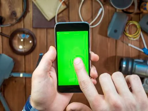 Close up phone with chroma key in the hand and wooden travel background Stock Photos