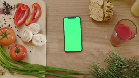 Close up phone with vertical green screen on wooden tablet around vegetables Stock Footage 144961916