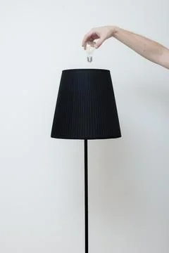 Close-up photo of A hand changes a light bulb in a stylish loft lamp from the Stock Photos