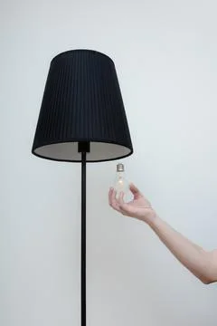 Close-up photo of A hand changes a light bulb in a stylish loft lamp Stock Photos