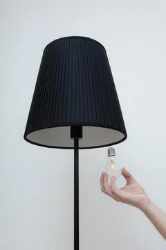 Close-up photo of A hand changes a light bulb in a stylish loft lamp Stock Photos