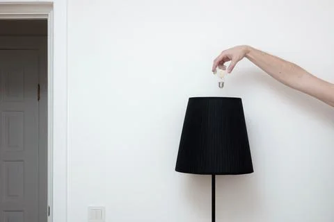 Close-up photo of A hand changes a light bulb in a stylish loft lamp from the Stock Photos