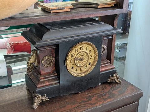An up-close photo of a large antique table clock with ornate gold details Stock-Fotos