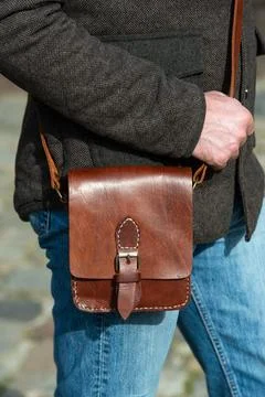 Close-up photo of light brown messanger leather bag on mans shoulder Stock Photos