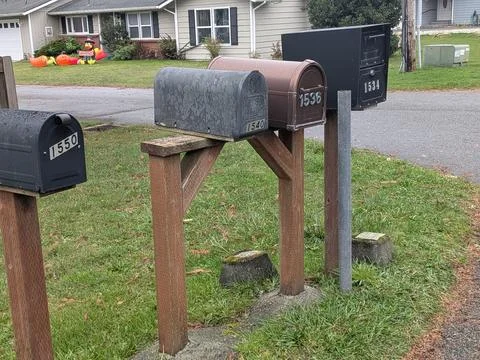 Close-up photo of multiple mailboxes mounted on wooden poles Stock Photos