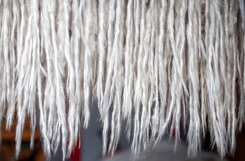 Close up photo of openwork handmade macrame decoration hanging on green wall in Stock Photos