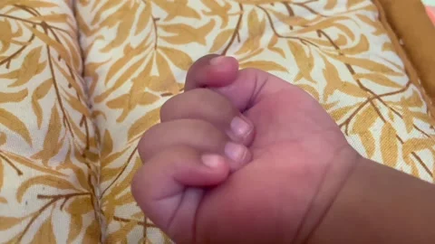 A close-up photo of a tiny, grasping baby's hand resting on a pillow. Vídeo Stock 344115355