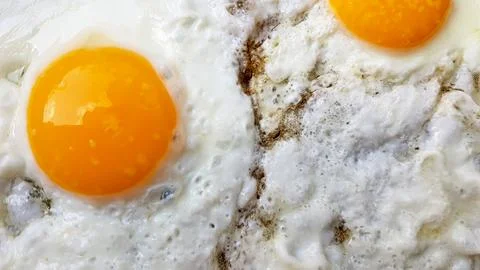 Close-up photo of two scrambled eggs in black frying pan Stock Photos