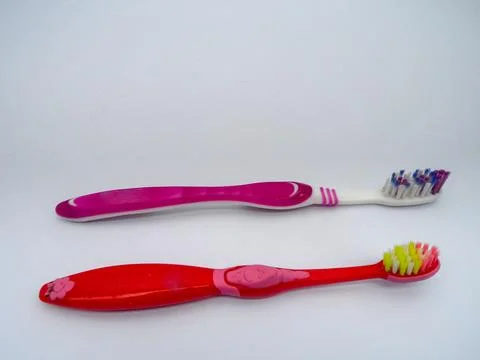 A close-up photo of two types of toothbrushes against a white background. Stock Photos