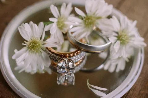 "Close-up photo of a wedding ring placed on glass, surrounded by flowers, s.. Foto stock
