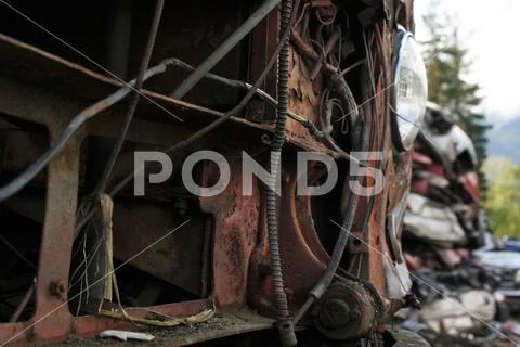 A close up photo of a wrecked vehicle with a stack of them in the background Stock Photos