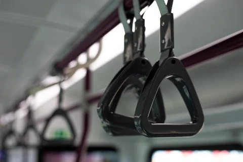 Close up photograph showing triangular hand straps hanging from ceiling, ty.. Stockfoto's