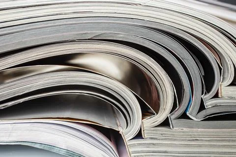 Close-up photograph of a stack of open magazines or journals, abstract text.. Stock Photos