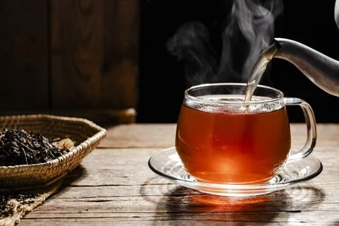 A close-up photograph of a teacup, with fragrant hot tea being poured into .. Stock Photos