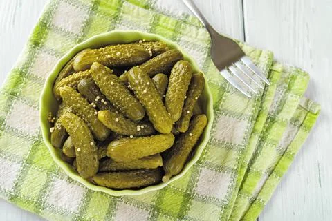 Close-up of pickled cornichons in a ceramic bowl on a green checkered napkin Stock Photos