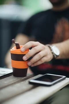 Close-up picture of guy drinking coffee to go on wooden table Foto stock