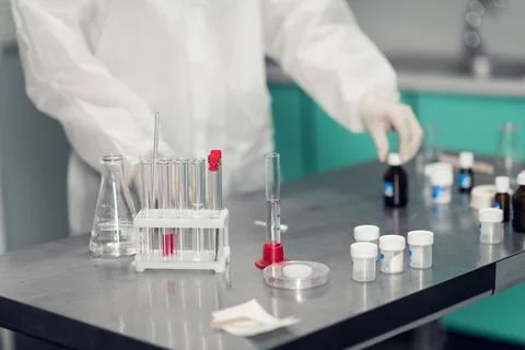 Close up picture of a lab table with the gloved hands of a worker carrying out Stock Photos