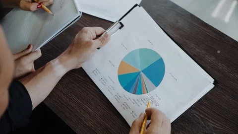 Close up of a pie chart and hands. International team working on statistical Video stock 98218605
