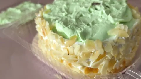 Close-up of a pie with nuts and cream in a plastic container. Texture of cream Stock Footage 324698254