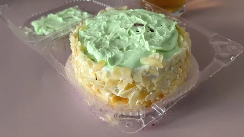 Close-up of a pie with nuts and cream in a plastic container. Texture of cream Stock Footage 324698300